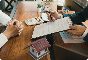 Two people discuss property investment and documents, preparing a Registration Statement Filing with a house model