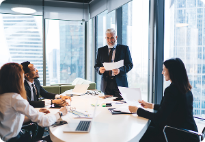 Business meeting: Senior executive presents details on section 16 filings to his diverse team in a bright modern office