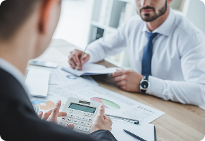 Accountant uses calculator during meeting about financial reports and iXBRL Filing with a client